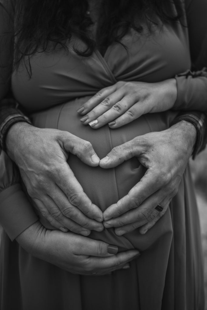 Creating a heart shape with hands in front of pregnant belly