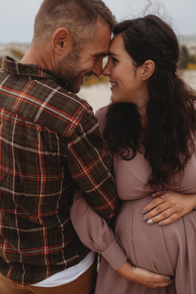 Young couple looking into each others eyes during Oregon Coast maternity session