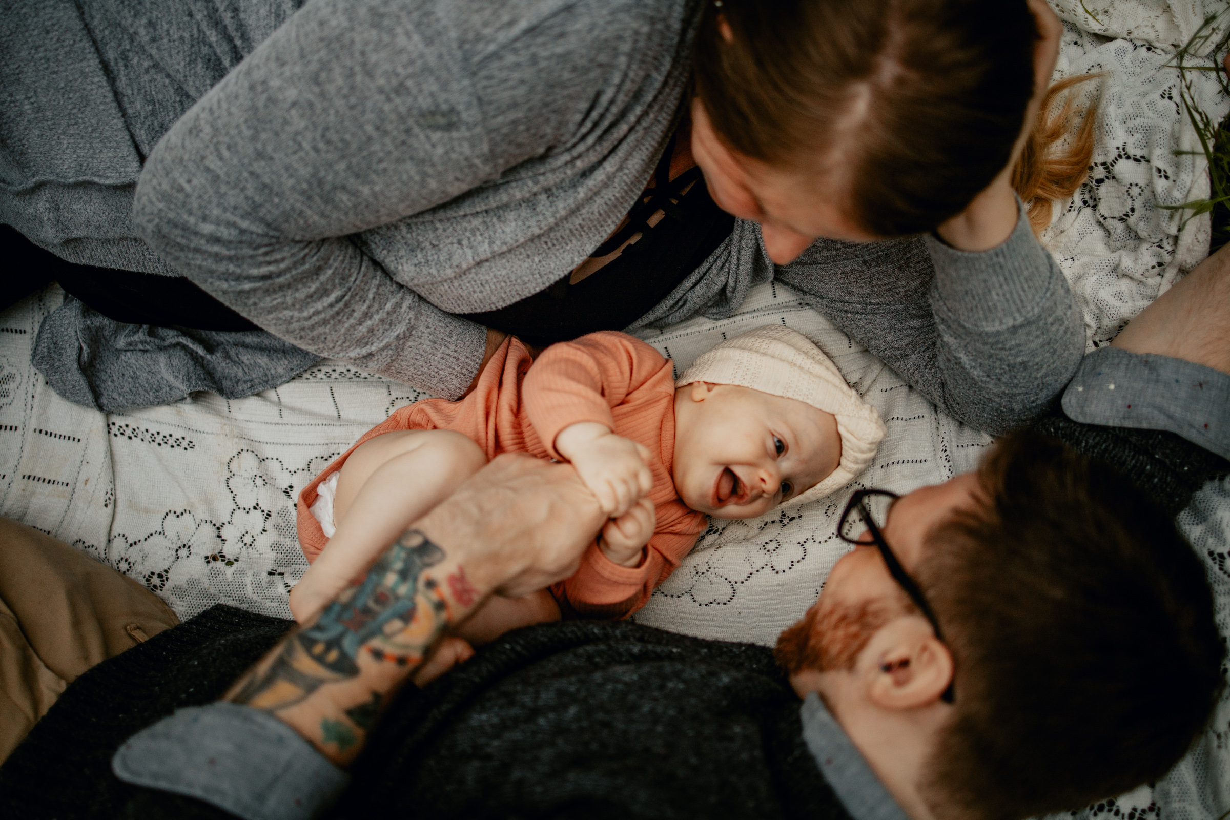 Parents cuddling their baby girl as they make her smile during family photos