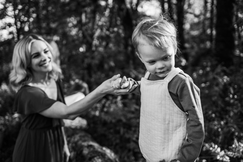 Mother holding sons hand as he explores nature during an outdoor family photography session with Lux Marina Photography