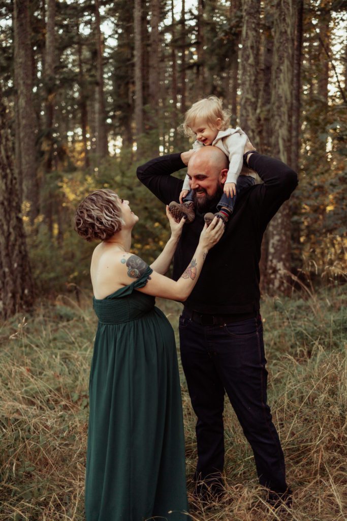 Young son on dads shoulders while mom tickles and laughs during pregnancy photos at Spencer Butte in Eugene Oregon