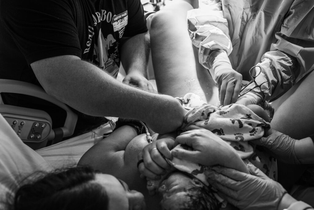 Father cutting umbilical cord documented by Lux Marina Photography offering birth photography to Eugene, Oregon and surrounding areas