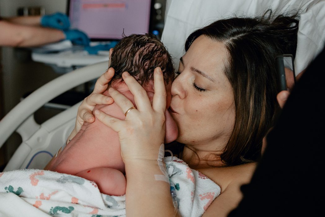 Mom kissing newborn baby minutes after giving birth