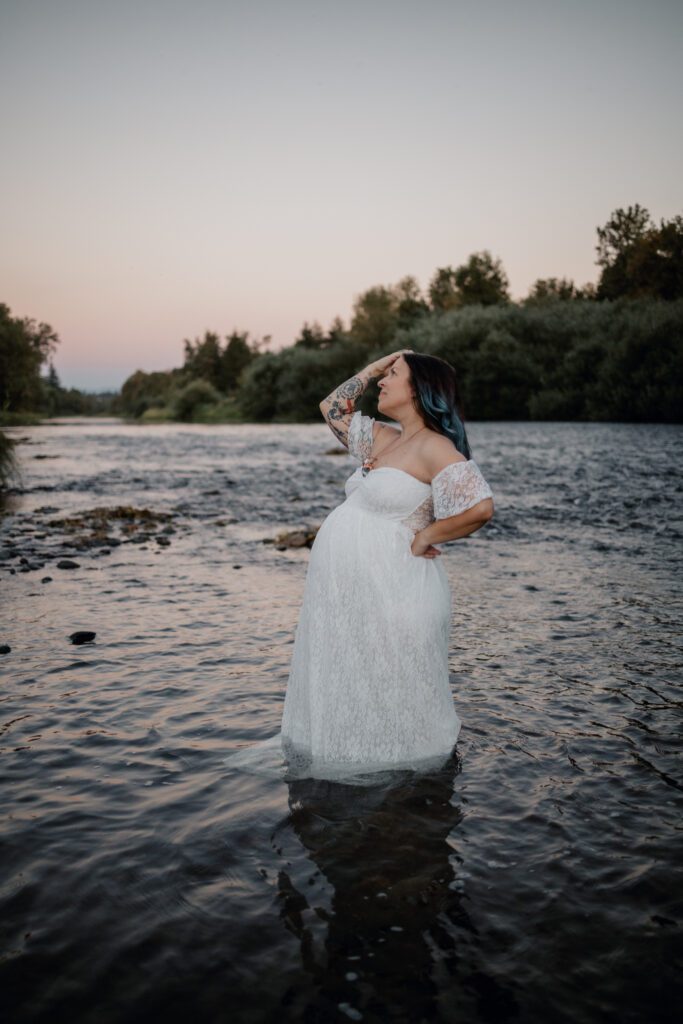 Beautiful pregnant woman in white dress standing in river at Mount Pisgah during personalized family photography session with Eugene Oregon family and birth photographer 