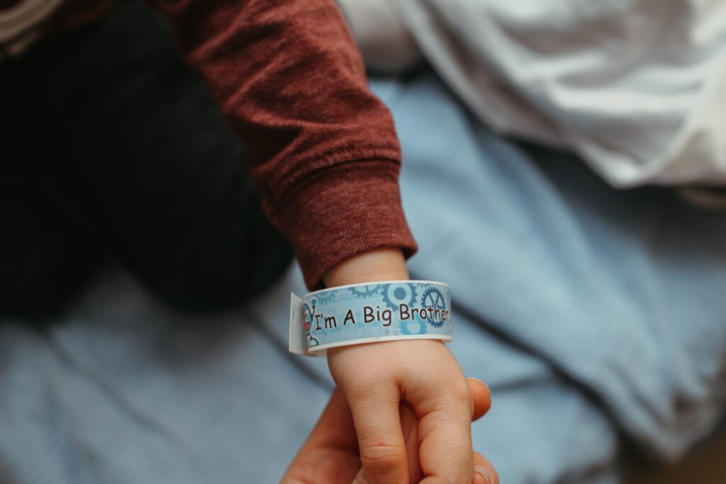 Big brother bracelet as loving toddler boy is promoted to big brother at fresh 48 session with Lux Marina Photography, Eugene, Oregon based baby photographer