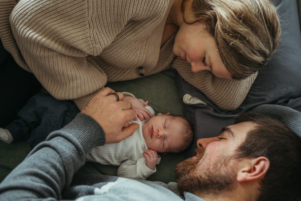 Parents laying down looking at newborn baby lovingly