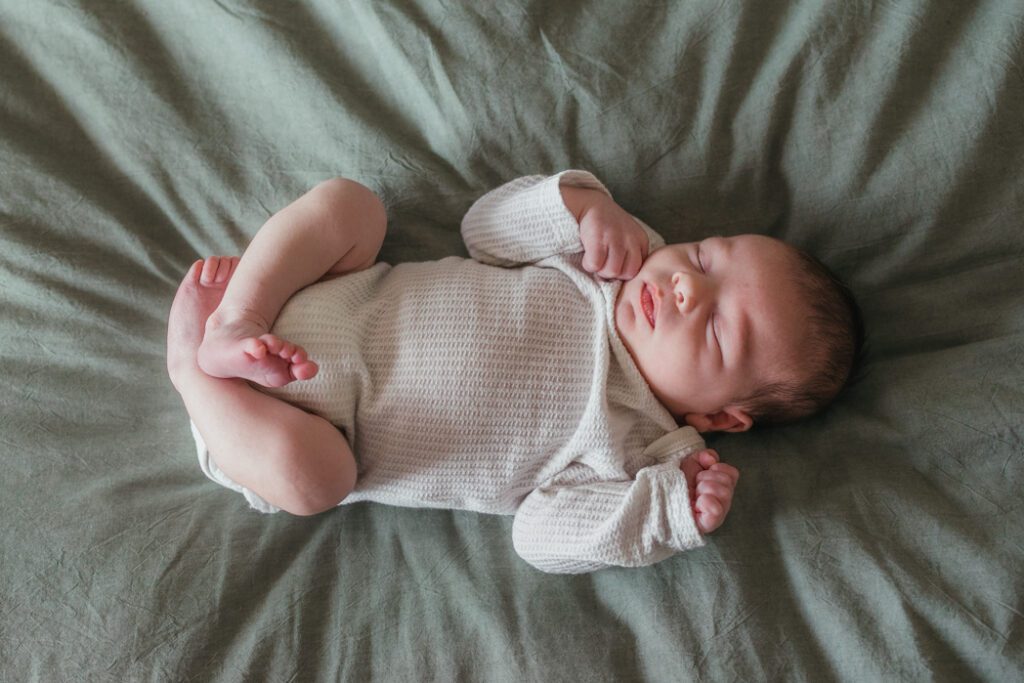 Newborn baby laying on bed sleeping during in home newborn session